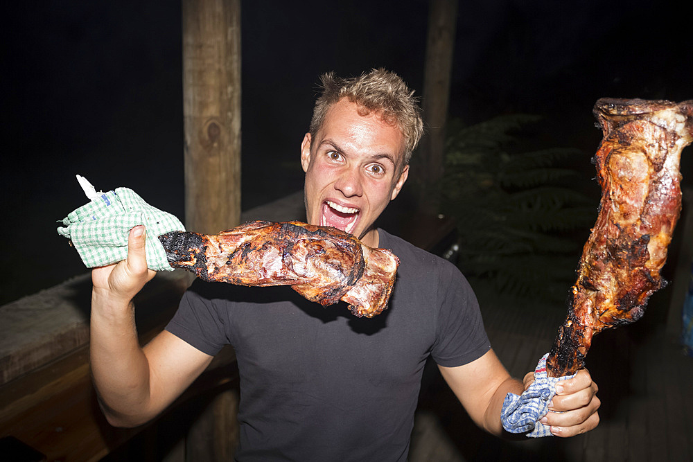 A man cooks and eats a goat that he hunted earlier in the day at Blue Duck Lodge; Whanganui National Park, Manawatu-Wanganui, North Island, New Zealand