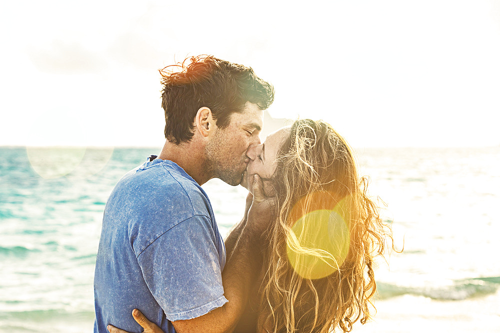 Close-up of millennial couple kissing on Lanikai Beach; Lanikai, Oahu, Hawaii, USA