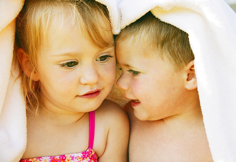 Two Kids Snuggle Under A Towel