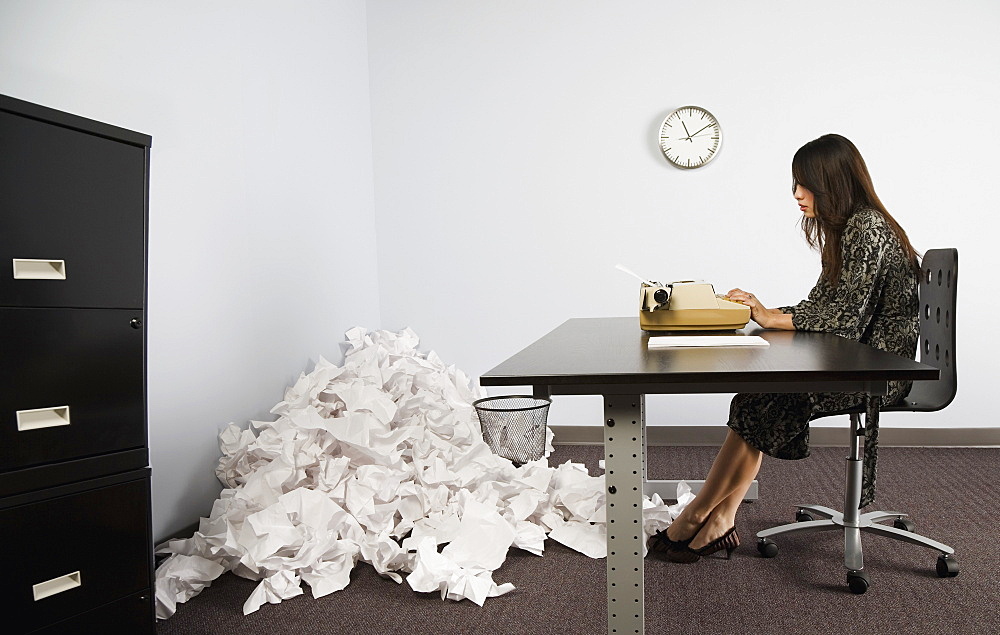 Businesswoman In Office With Crushed Pile Of Paper On Floor