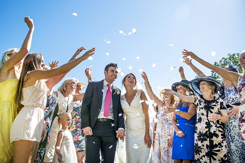 A bride and groom are showered with confetti on their wedding day