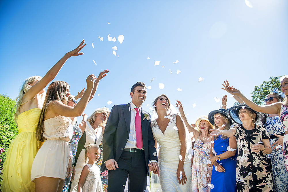 A bride and groom are showered with confetti on their wedding day