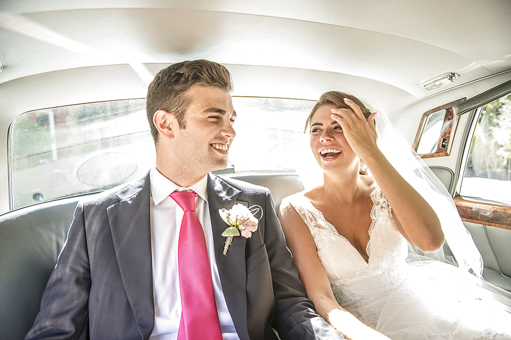 A bride and groom sit in the wedding car after getting married