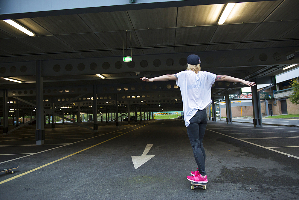 A cool young tattooed skater girl having fun with a skateboard.