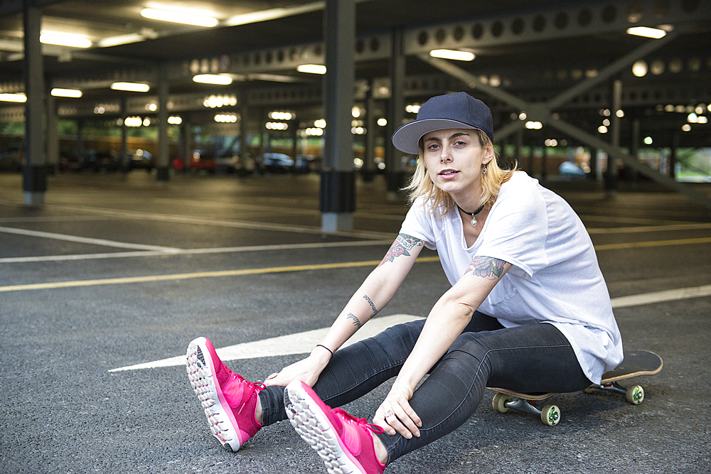 A cool young tattooed skater girl having fun with a skateboard.