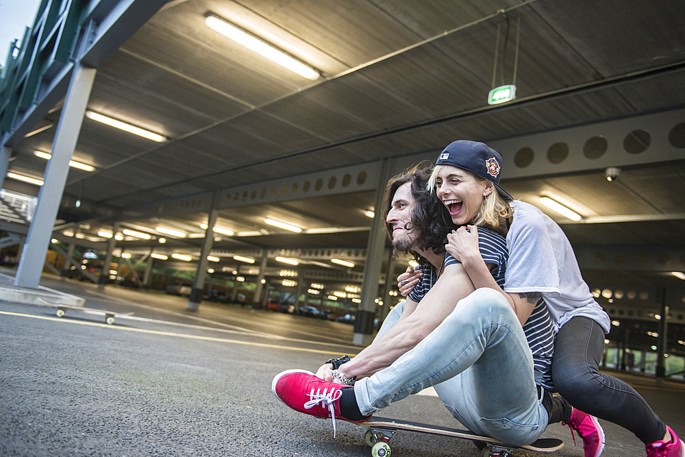 A cool young couple having fun with a skateboard.