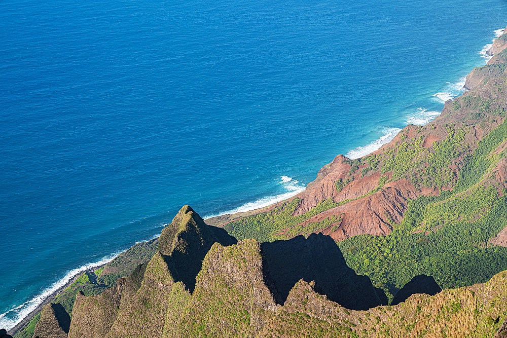 Scenic view from the green covered mountain cliffs of the Napali Coast along the Kalalau Trail on the Hawaiian Island of Kauai, with the calm, blue waters of the Pacific Ocean lapping the shore, Kauai, Hawaii, United States of America