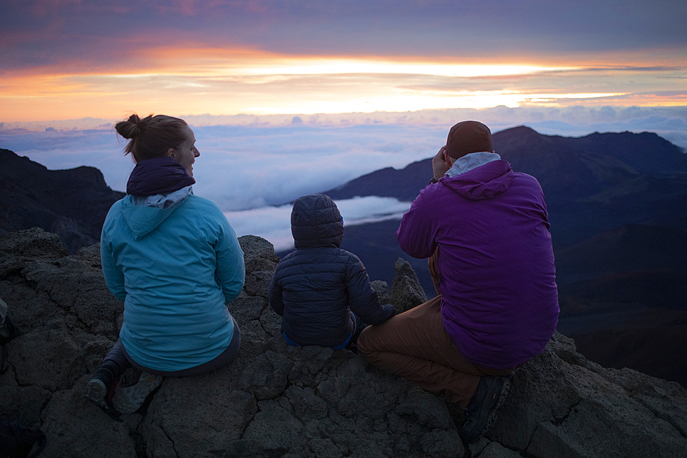 Family on a mountain top above the clouds at Haleakala watching the sunrise over the Pacific Coast, Haleakala National Park, Maui, Hawaii, United States of America