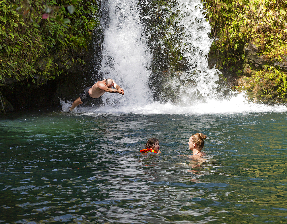 Family enjoying swimming in a natural pool under a plunging waterfall along the Road to Hana, Maui, Hawaii, United States of America