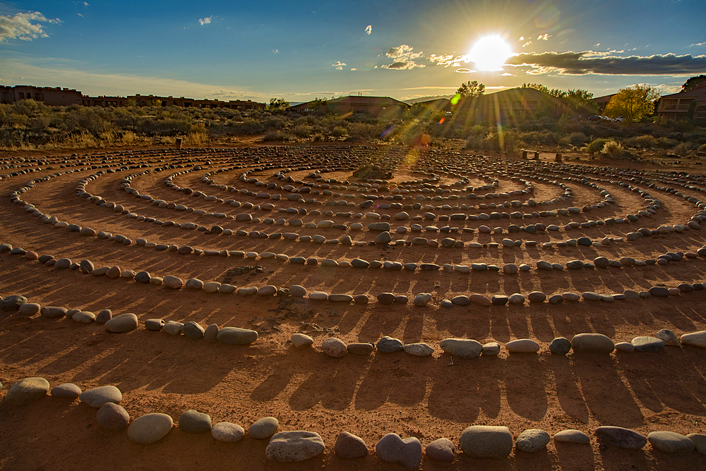 Hiking trail through Snow Canyon, with circles of stones in a meeting area behind the Red Mountain Spa, with meditation maze and Snow Canyon Mountain Range in the background. Red Cliffs Desert Reserve around St George Town with bright sunburst in a blue sky, St George, Utah, United States of America