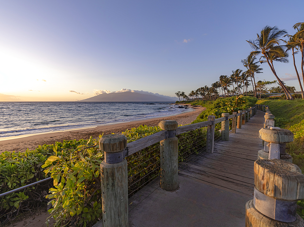 Wooden walkway along the shore of a luxury resort at Keawakapu Beach with view of the Pacific Ocean at twilight, Kihei, Wailea, Maui, Hawaii, United States of America