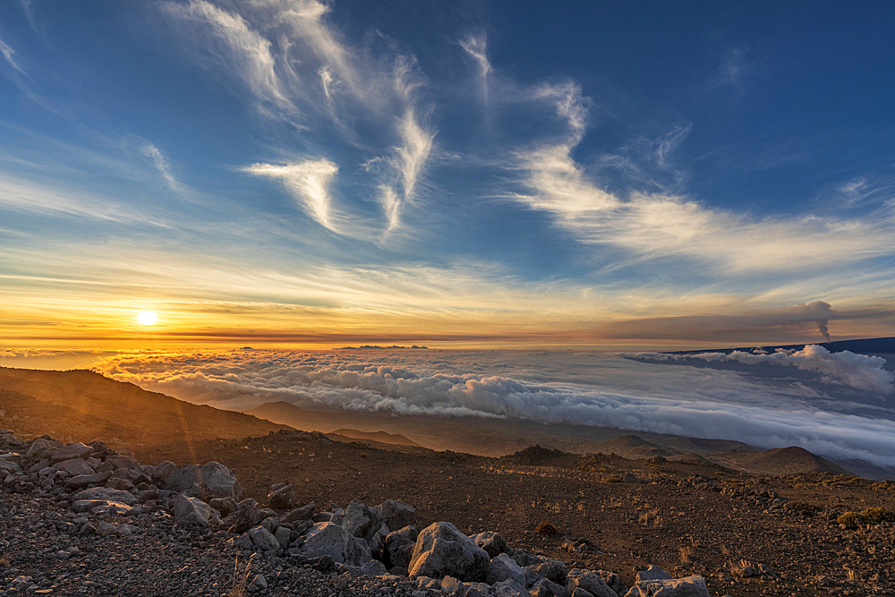 Spectacular scene of the golden twilight above the clouds at Mauna Kea with view of the smoke from 2022 eruption of Mauna Loa Volcano (Moku‘āweoweo, the world's largest active volcano) on the Big Island of Hawaii, Island of Hawaii, Hawaii, United States of America