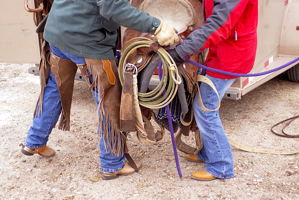 Ranch couple work together to lift a saddle into a trailer, Halsey, Nebraska, United States of America