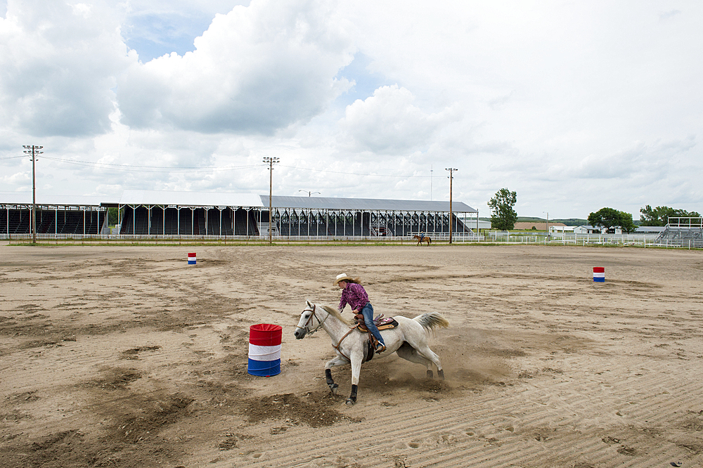 Teenage girl practices barrel racing with her horse, Burwell, Nebraska, United States of America