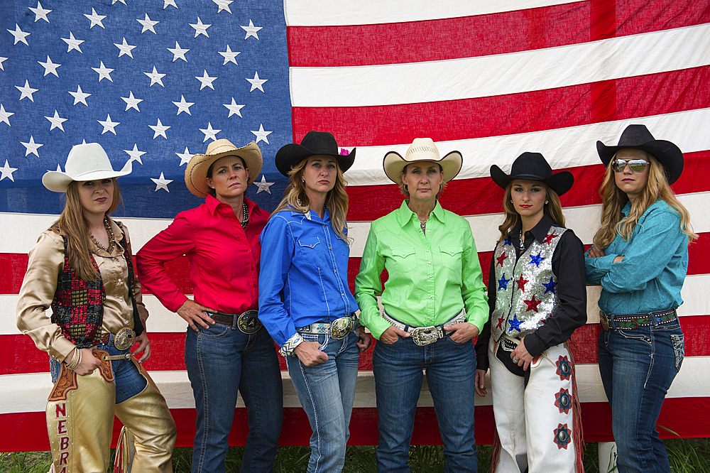 Rodeo queens pose for a portrait in front of an American flag, Burwell, Nebraska, United States of America