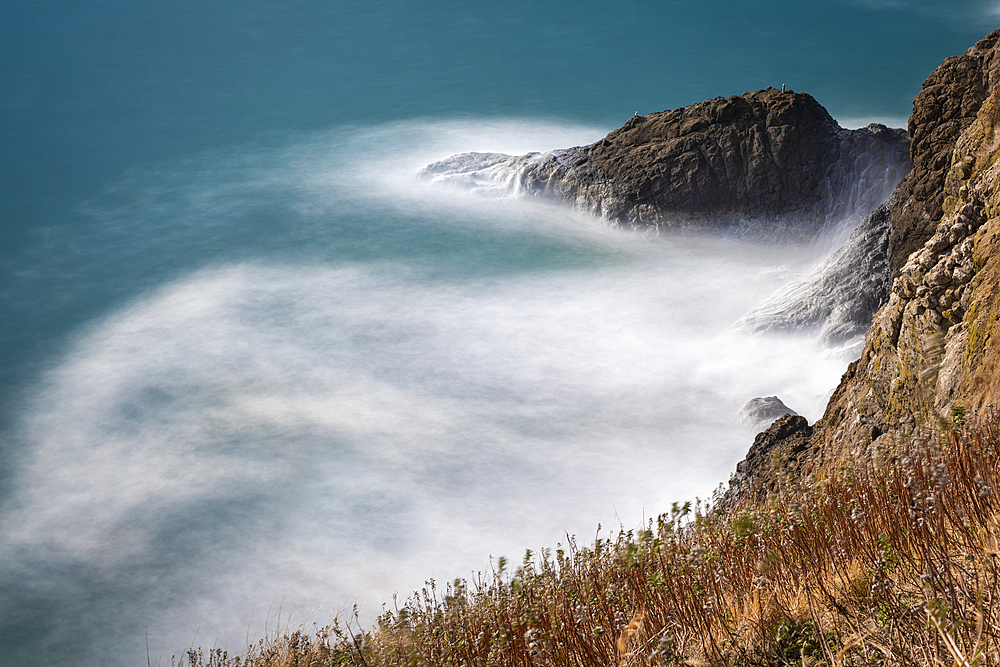 Long exposure of frothy waves crashing into the cliffs at Cape Disappointment, at the mouth of the Columbia River in Southwest Washington, Washington, United States of America