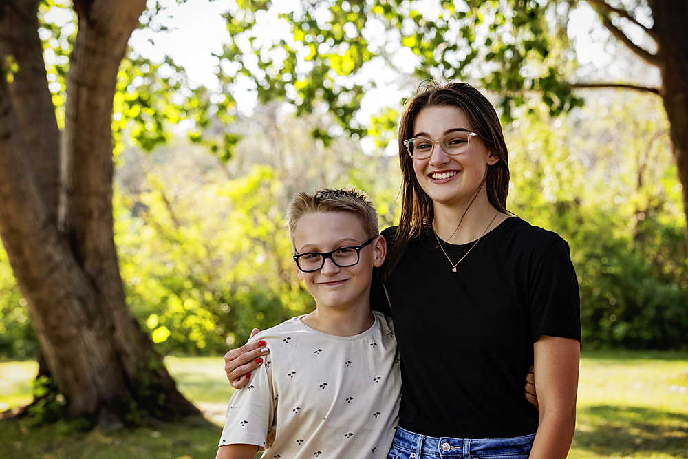 Outdoor portrait of two siblings in a loving relationship, spending quality time together in a city park during a warm fall afternoon, Leduc, Alberta, Canada