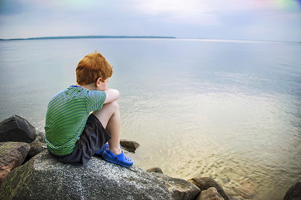 Young boy stares out over the water of Leech Lake in Minnesota, USA, Leech Lake, Minnesota, United States of America