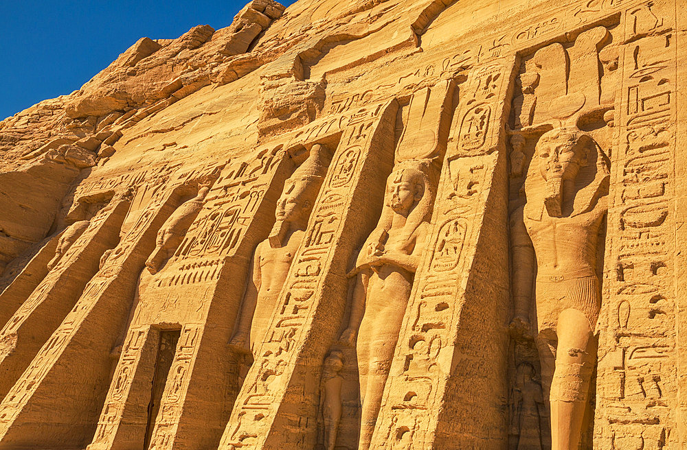 The six standing colossal statues honoring Hathor the Goddess of Music and Love and Ramses II's wife, Nefertari in front of the Temple of Hathor at Abu Simbel, Abu Simbel, Nubia, Egypt