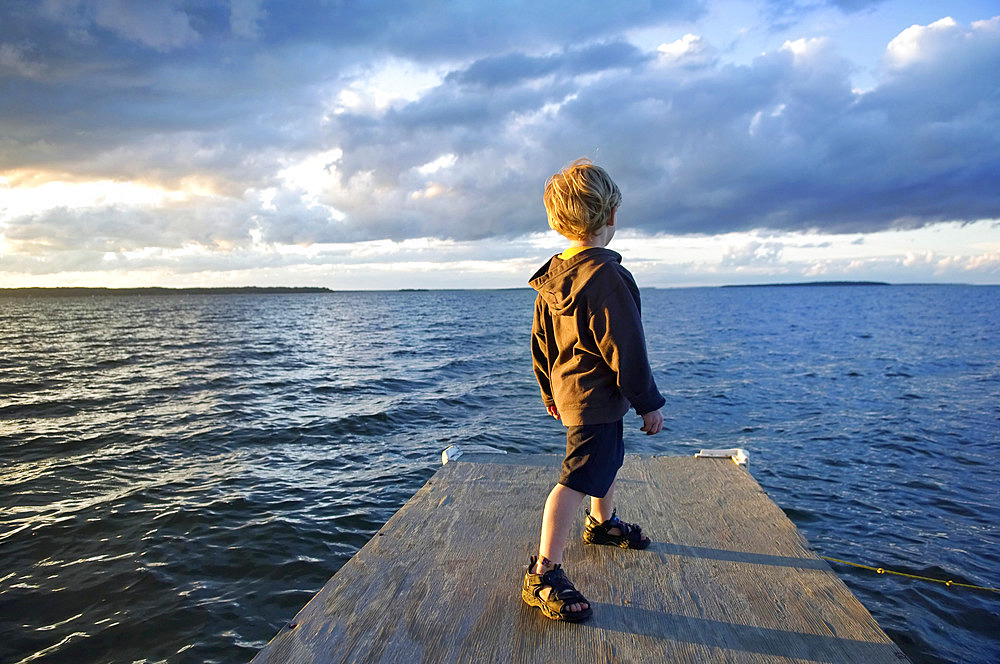 Young boy on a dock at the lake at dusk, Leech Lake in Minnesota, USA, Walker, Minnesota, United States of America