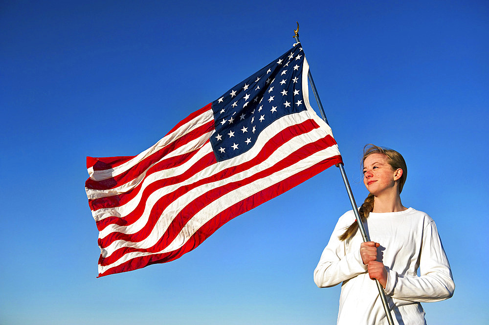 Teenage girl proudly holds an American flag, Lincoln, Nebraska, United States of America