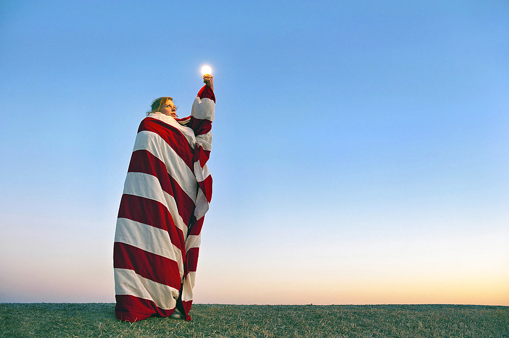 Young woman poses like the statue of liberty with a light bulb, Lincoln, Nebraska, United States of America