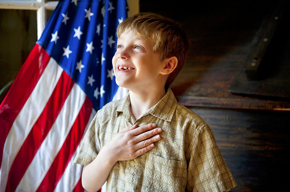 Young, patriotic boy stands before the American flag, Lincoln, Nebraska, United States of America