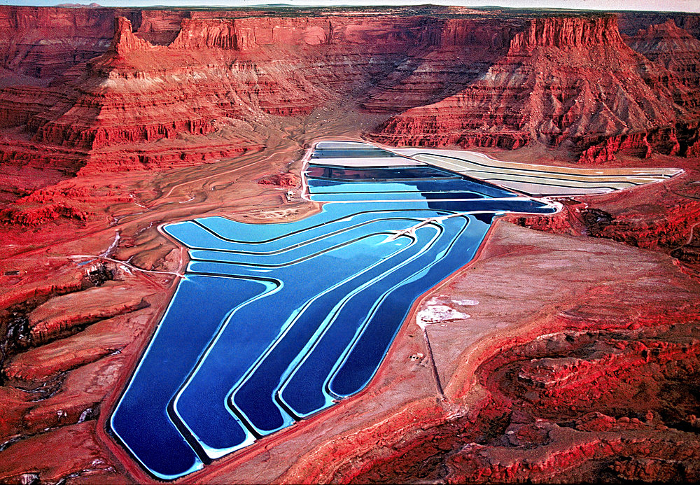 Aerial view of TexasGulf Potash Ponds which are solar evaporation ponds used in the process of mining potash. Potash, a water-soluble potassium salt is extracted and blue dye is added to increase the rate of evaporation. It is mainly used in fertilizer products but also in the making of soap, glass, ceramics and batteries. The mine is currently owned and operated by Intredpid Potash Inc and the ponds cover 400 acres of land surrounded by sandstone cliffs and wilderness near Moab, Utah, USA, Utah, United States of America