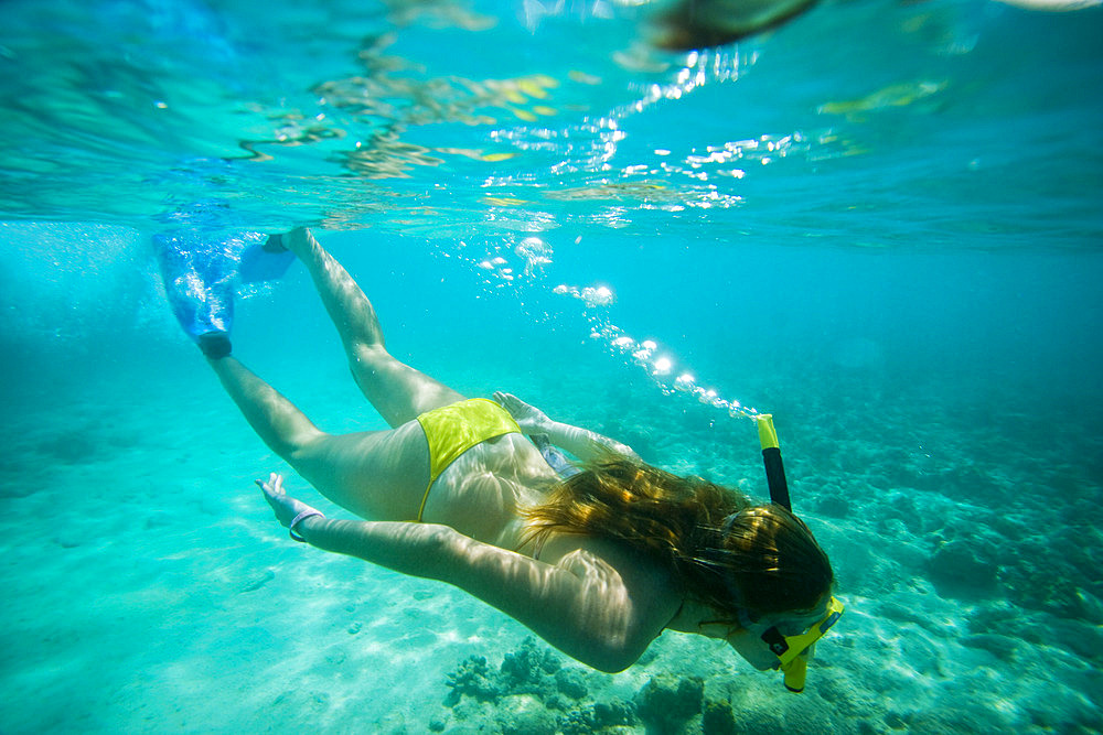 Teenage girl snorkeling in a yellow bikini, Country of Aruba