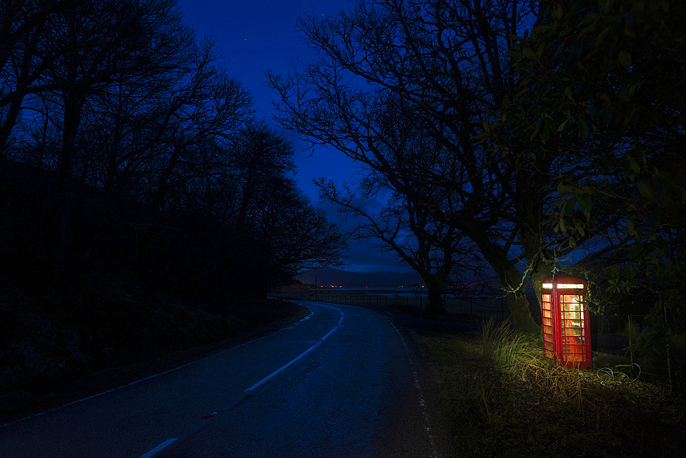 Phone box illuminated at night on a quiet road near Corran on the Ardnamurchan Peninsula, Scotland