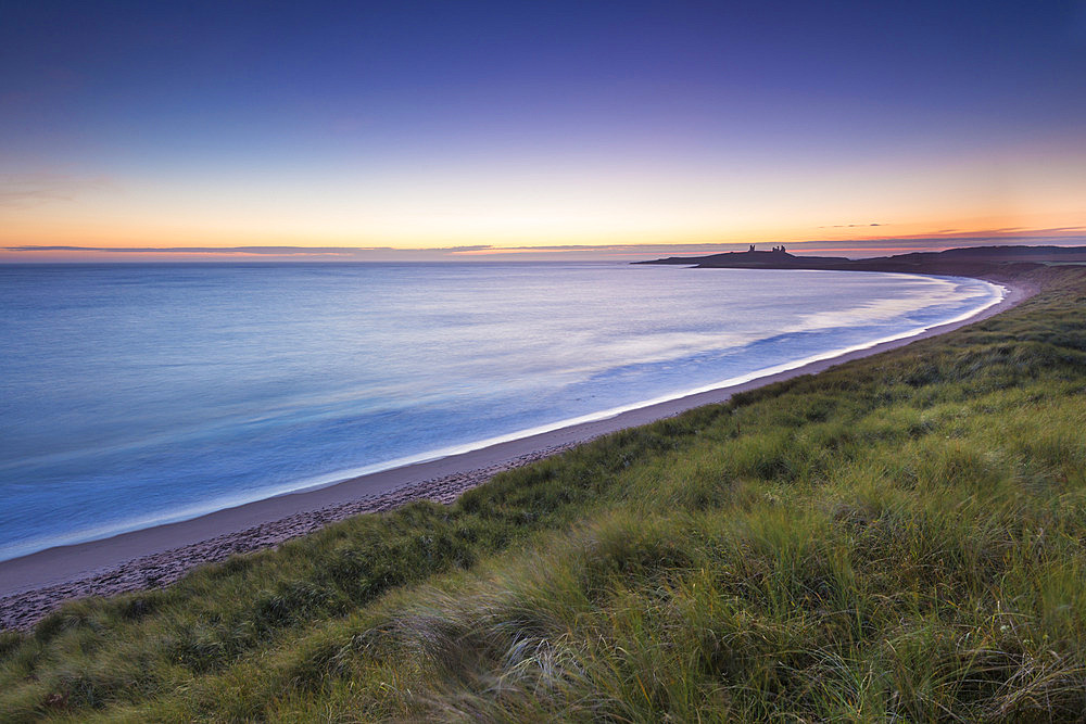 Embleton Beach at dawn with Dunstanburgh Castle in the distance, Northumberland, England, United Kingdom