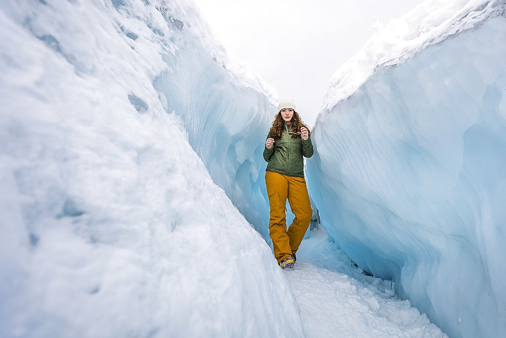 Teenage girl walking on the Matanuska Glacier in between blue ice walls, Sutton, Alaska, United States of America