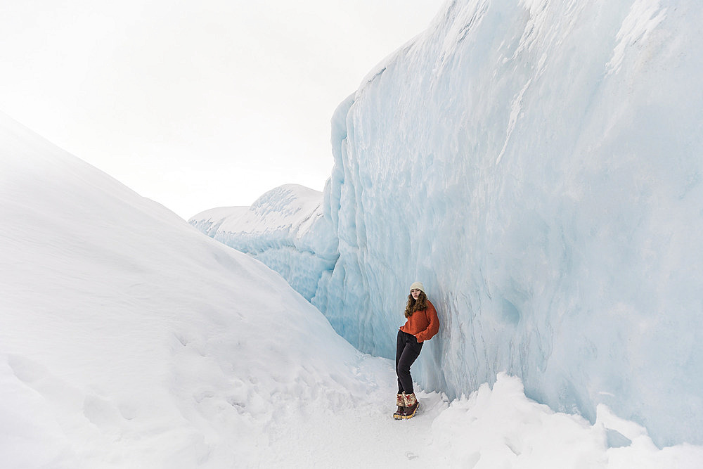 Teenage girl leaning against ice walls on the Matanuska Glacier in Sutton, Alaska, Sutton, Alaska, United States of America