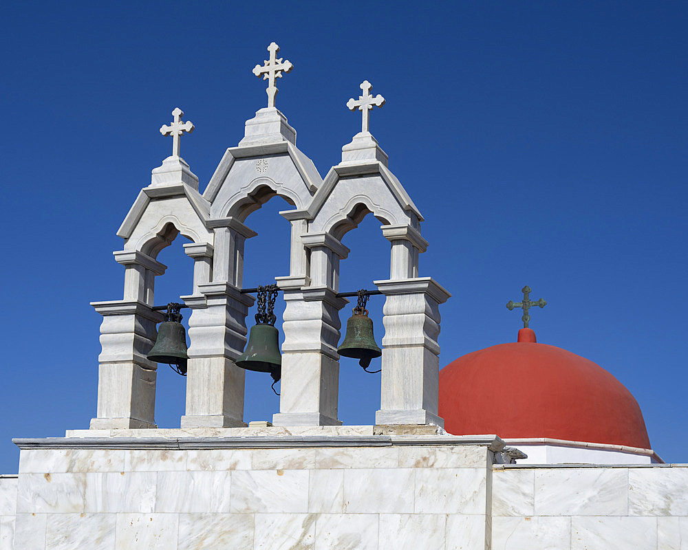 Architectural detail of bells and crosses and a red dome on the Panagia Tourliani Monastery against a bright blue sky in Mykonos, Greece, Ano Mera, South Aegean, Greece