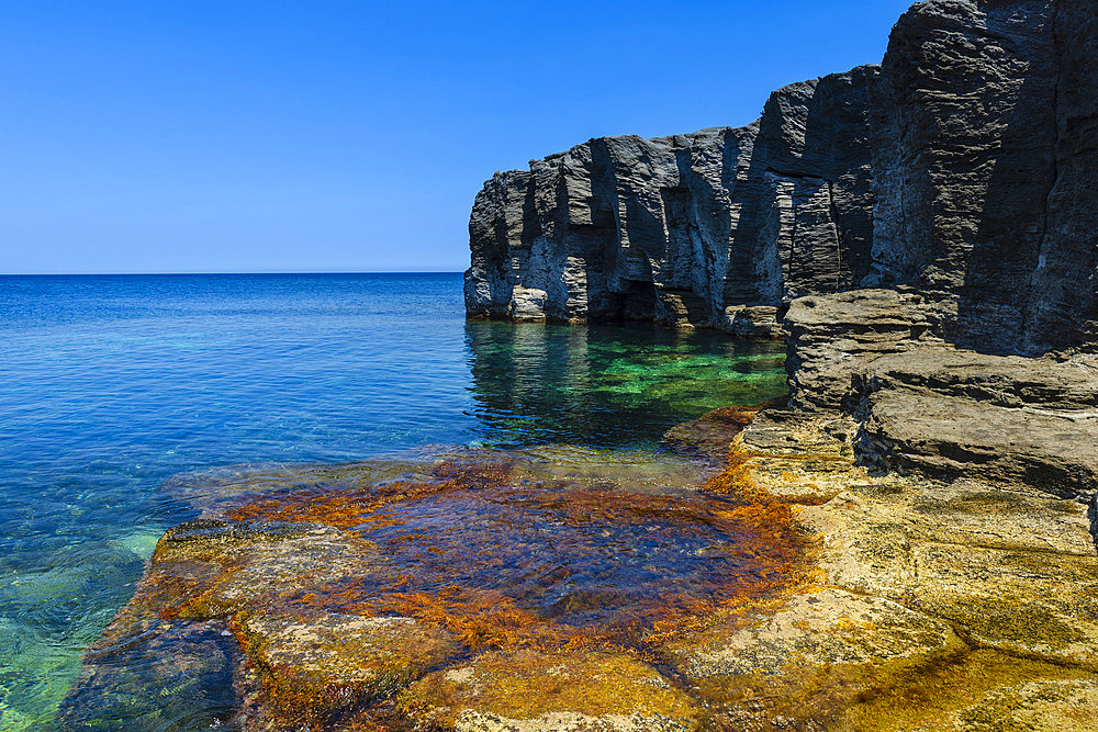 Scenic view of the volcanic rock cliffs and shoreline at Cala del Bue Marino on Pantelleria Island on a sunny day, Pantelleria Island, Trapani, Sicily, Italy