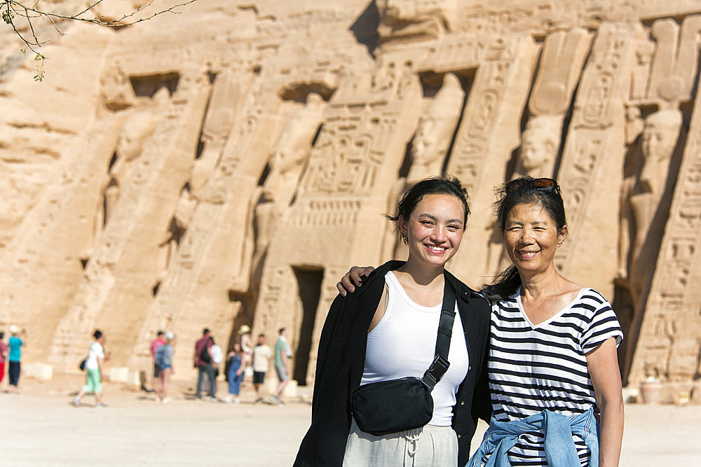 Mother and daughter tourists standing in front of the Temple of Hathor at Abu Simbel, Aswan, Nubia, Egypt