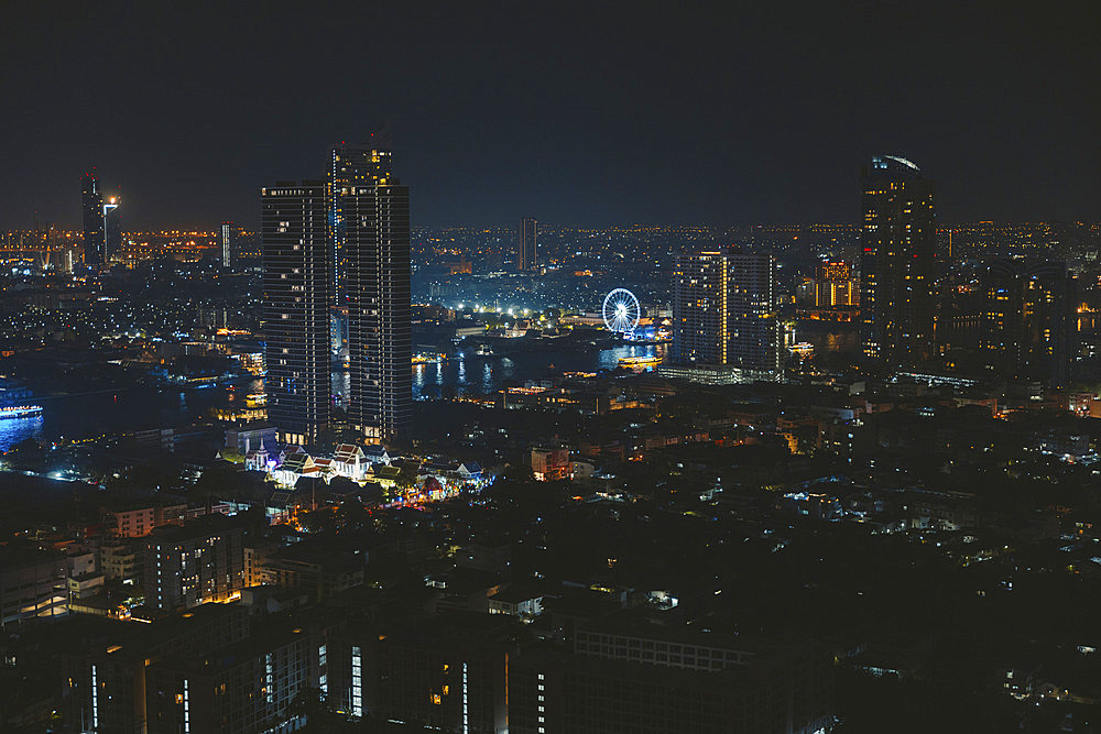 Cityscape at night with illuminated observation wheel on the waterfront