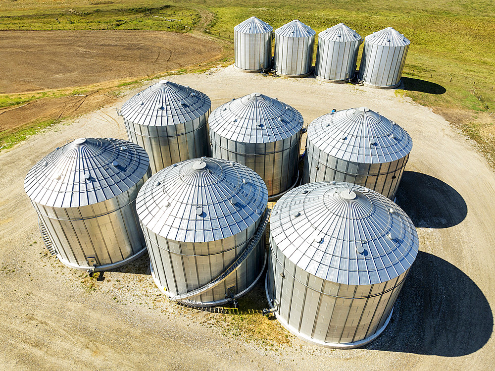 Aerial view of large metal grain bins on farmland North of Calgary, Alberta, Alberta, Canada