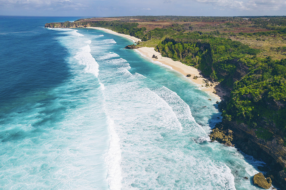 Aerial view of the expanse of Mbawana Beach with the surf rolling into the white sand and rugged coastline, East Nusa Tenggara, Indonesia, Kodi Bangedo, Southwest Sumba Regency, East Nusa Tenggara, Indonesia