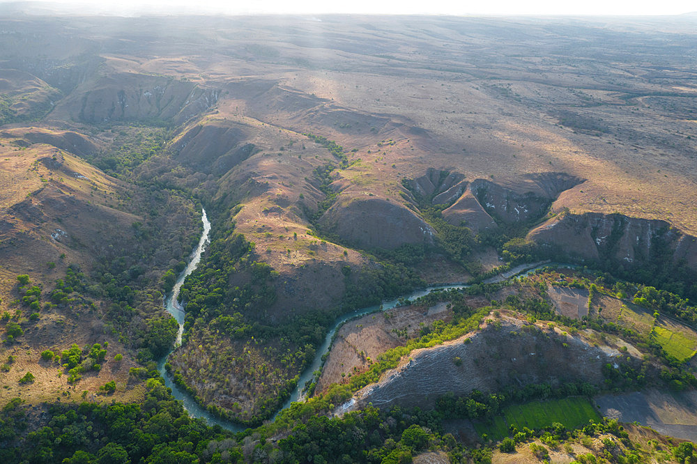 View of the winding river and hilly landscape with sunlight from Ndapayami Hill, East Nusa Tenggara, Indonesia;