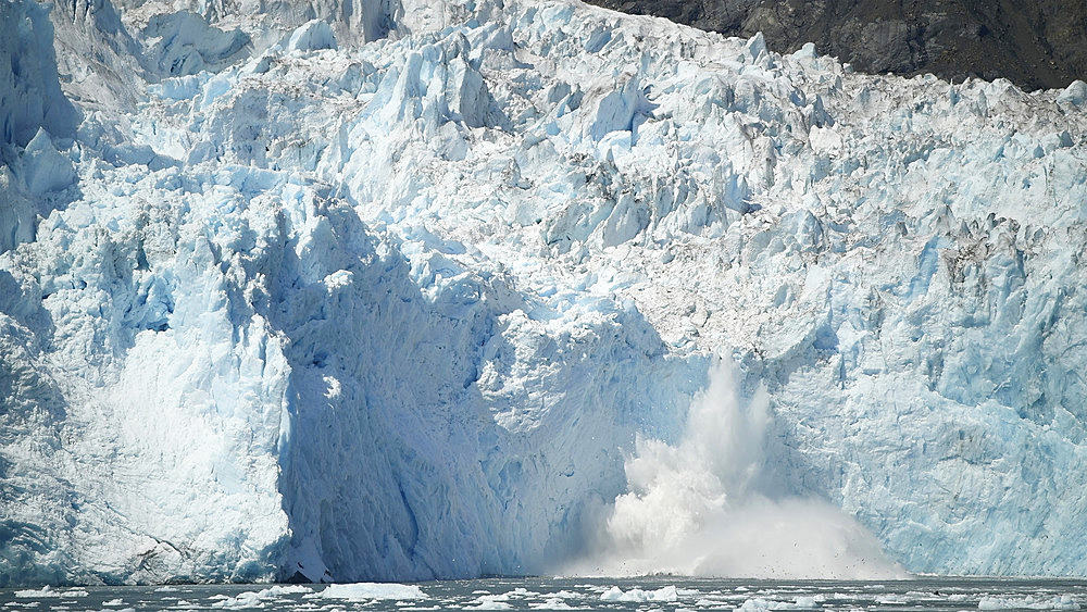 Large splash in the ocean after a piece of glacier calves off into the ocean, Whittier, Alaska, United States of America