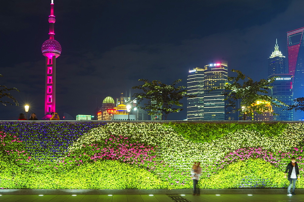 Vegetal wall on the Bund and view over Pudong financial district skyline at night, Shanghai, China, Asia