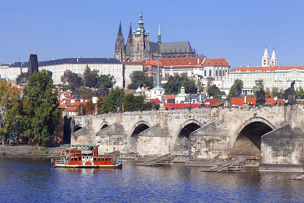 View over the River Vltava with excursion boat to Charles Bridge and the Castle District with St. Vitus Cathedral and Royal Palace, UNESCO World Heritage Site, Prague, Bohemia, Czech Republic, Europe