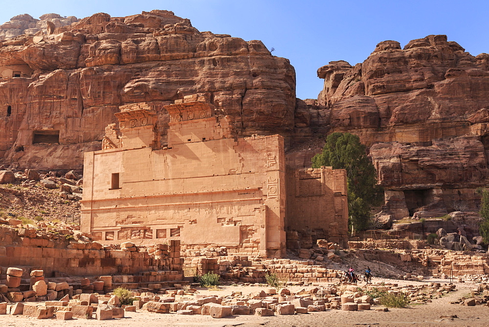 Local men on donkeys pass Qasr al-Bint temple, City of Petra ruins, Petra, UNESCO World Heritage Site, Jordan, Middle East