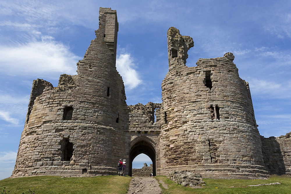 Walkers arrive at historic Dunstanburgh Castle, Northumberland, England, United Kingdom, Europe