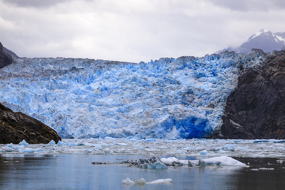 Ice pack and blue ice face of South Sawyer Glacier, mountain backdrop, Stikine Icefield, Tracy Arm Fjord, Alaska, United States of America, North America