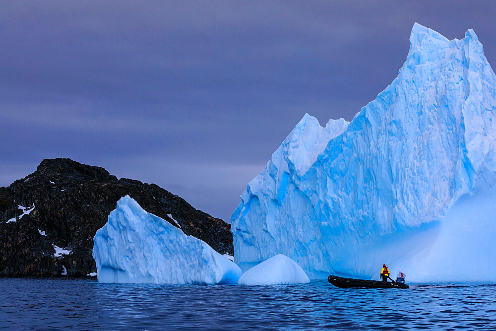 Person in zodiac looks at a huge blue iceberg, near Torgersen Island, Anvers Island, Antarctic Peninsula, Antarctica, Polar Regions