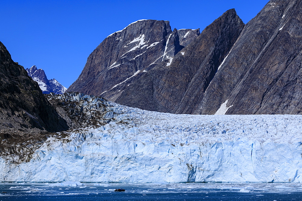 Cruise passengers in zodiac give scale to huge face, Thryms Glacier, Skjoldungen Fjord, glorious weather, remote East Greenland, Denmark, Polar Regions