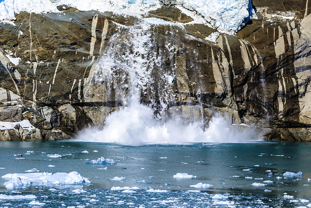 Calving glacier, chunks of ice fall from glacier into Skjoldungen Fjord, creating huge splash, remote South East Greenland, Denmark, Polar Regions