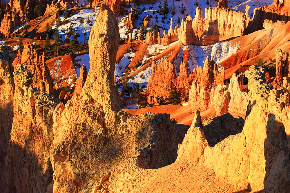 Hoodoos and snow lit by strong dawn light in winter, Queen's Garden Trail at Sunrise Point, Bryce Canyon National Park, Utah, United States of America, North America